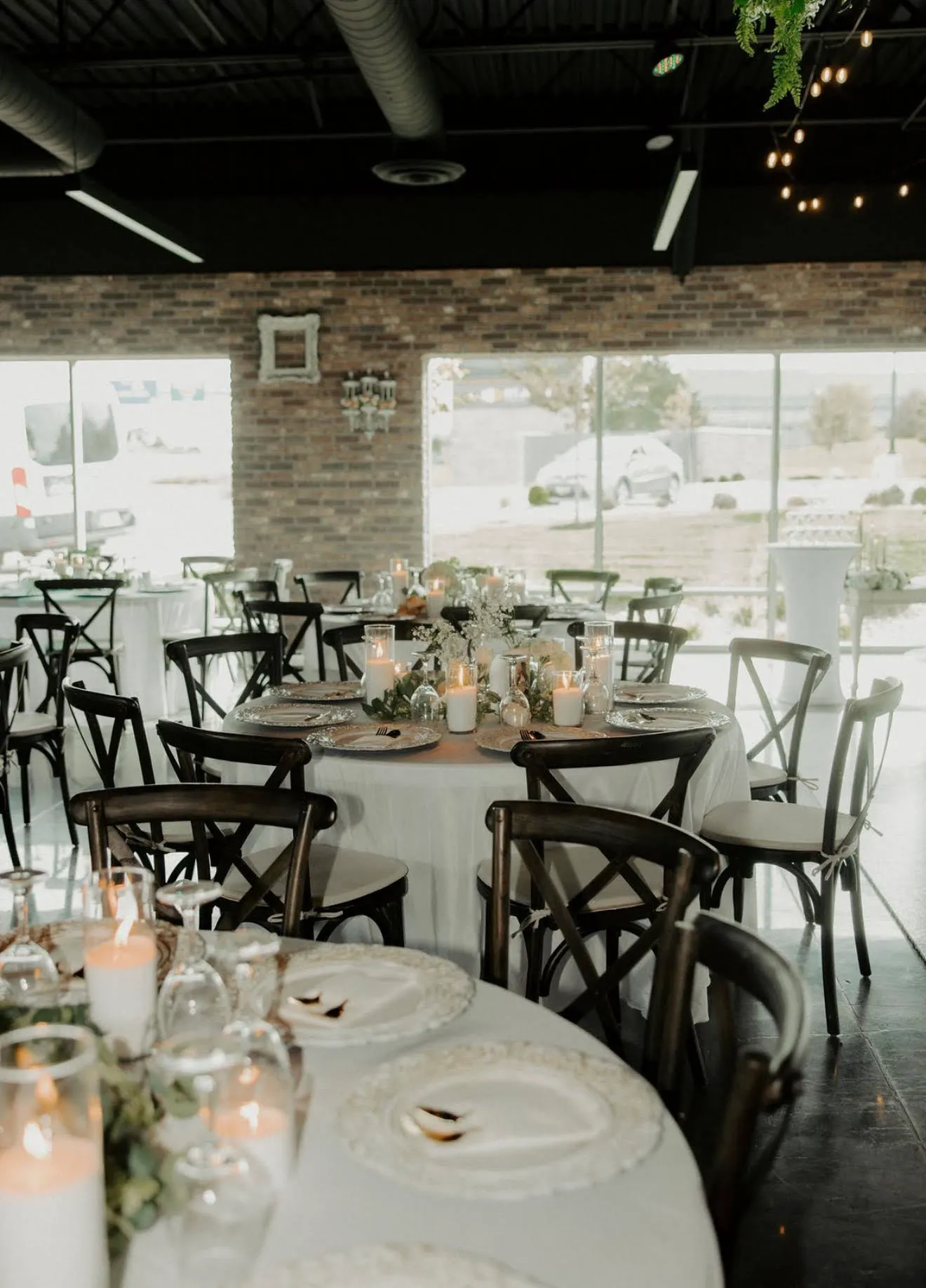 Round tables in white linen with candles and dark wood chairs