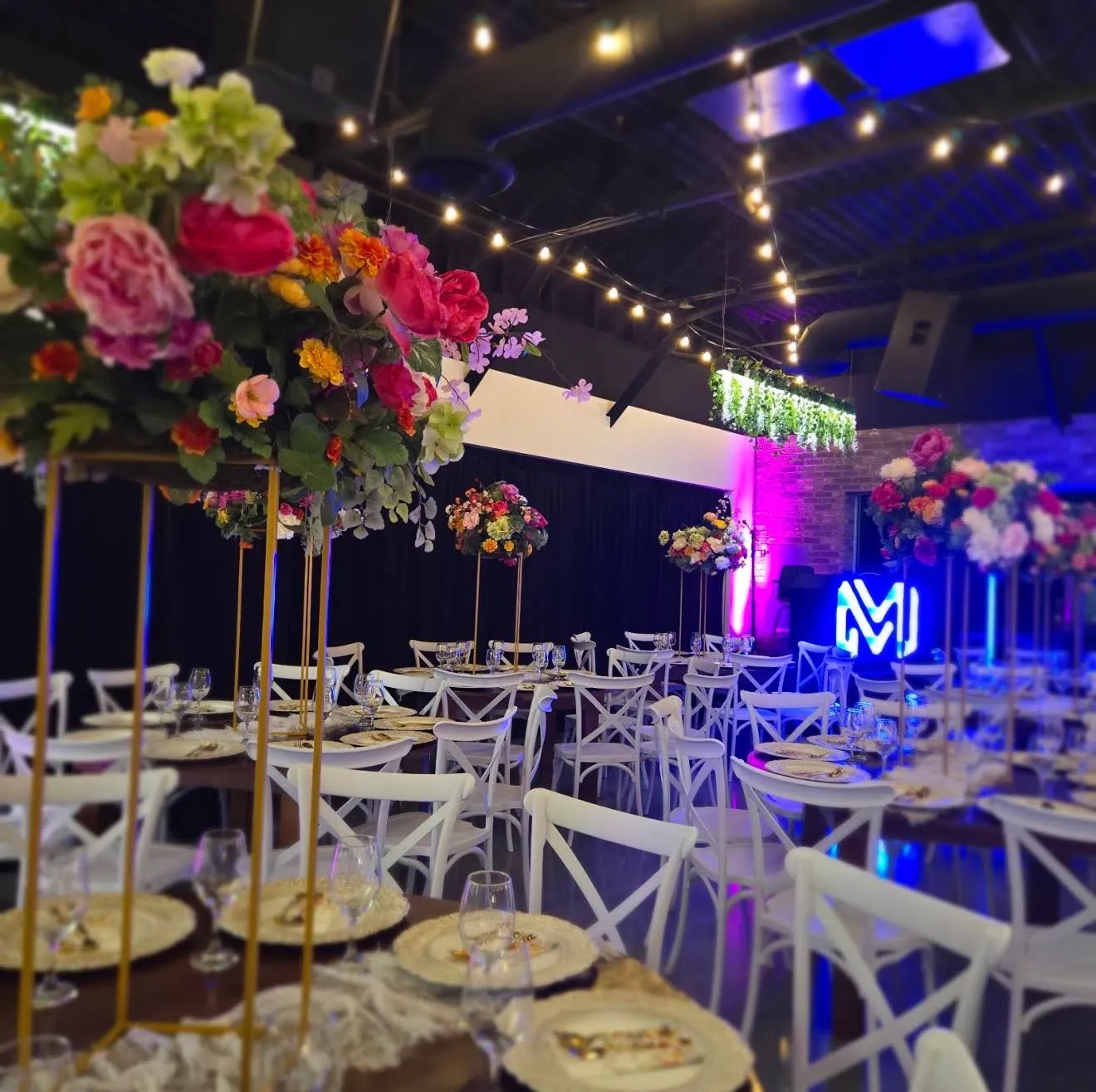 Tall floral centerpieces with the lit M monogram behind