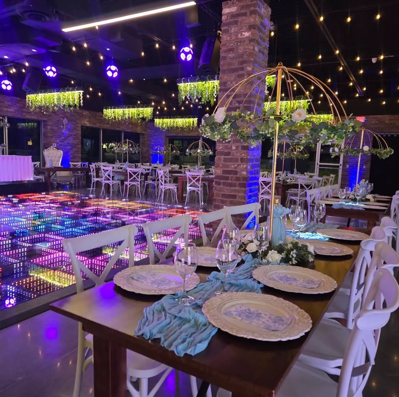 A table with blue runners beside the multicolor LED dance floor