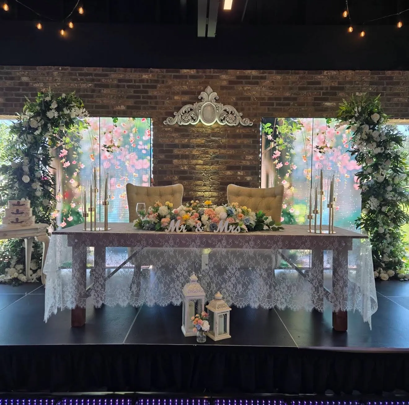 The sweetheart table on the stage with flowers, candelabras and Mr & Mrs letters
