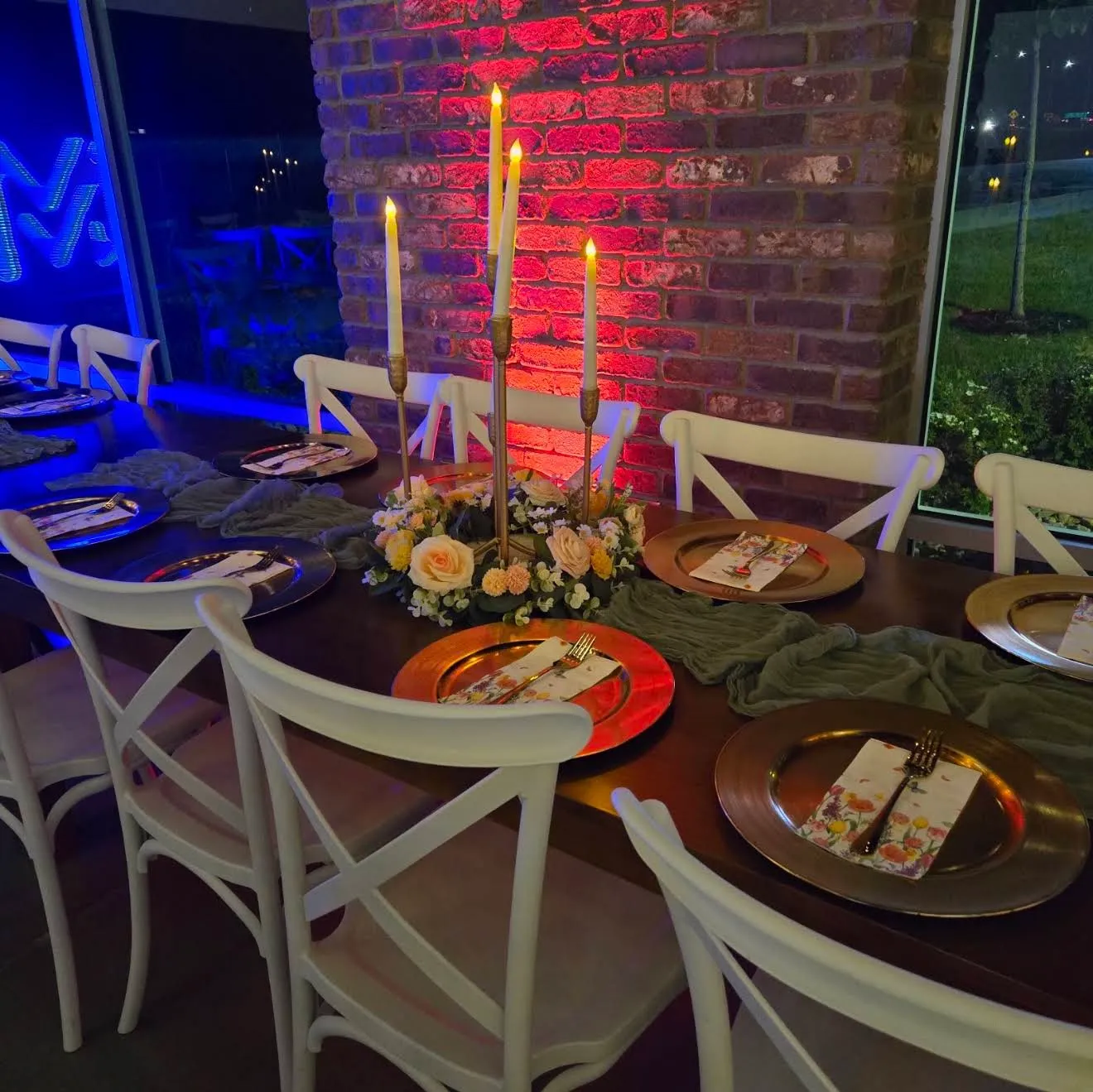 A table with gold chargers and a candelabra against the lit brick wall